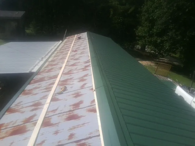 Old rusted panels beside newly installed green metal roofing — Wind Damage Roof Repair by Roofing Brothers in Rio Vista