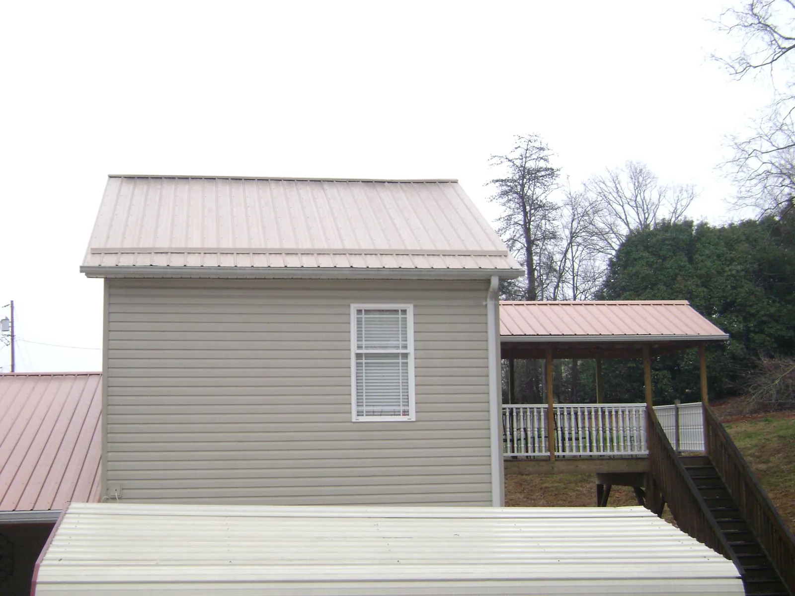 Tan metal roofs on a two story addition and attached porch, from a Roof Replacement job in Rio Vista