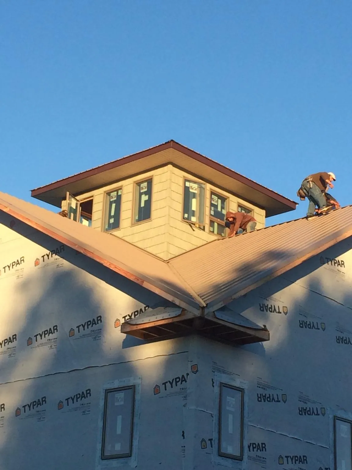 Roofers working around a rooftop cupola on a new metal roof at sunset — Roof Waterproofing in Rio Vista by Roofing Brothers